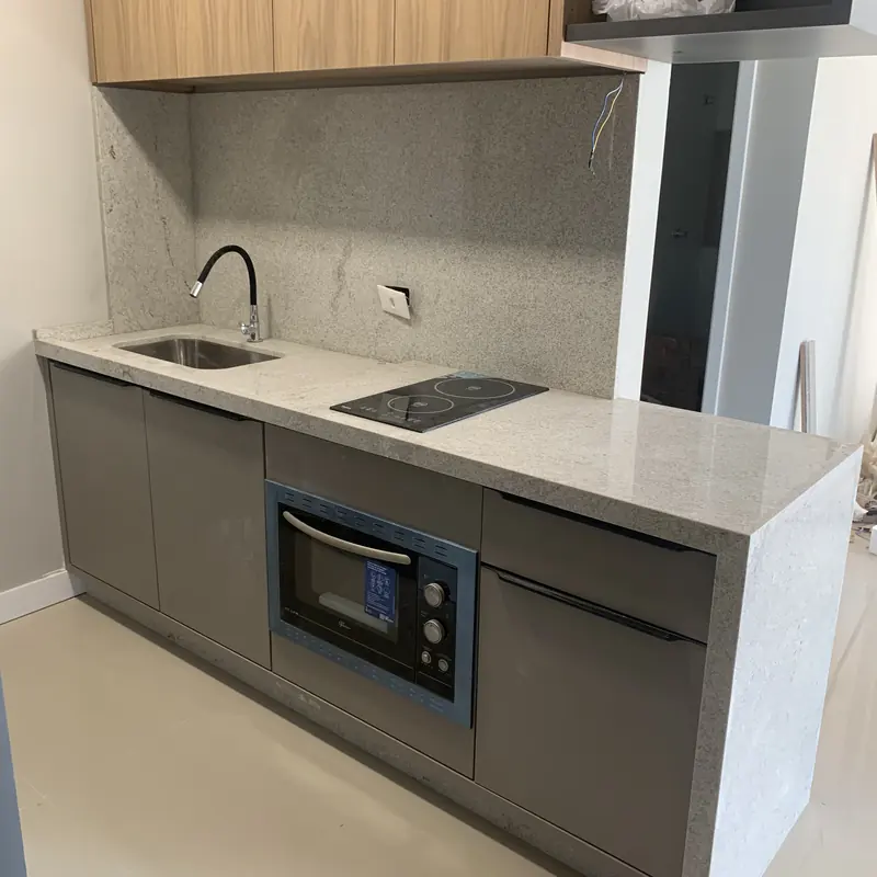 Bancada clara com cooktop, cuba e frontão em pedra