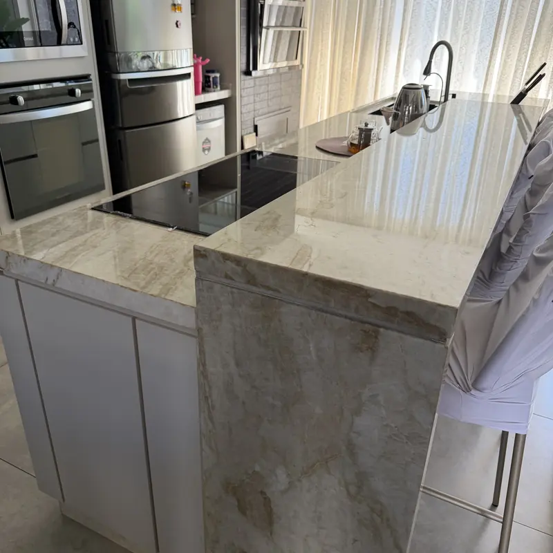 Ilha com cooktop e lateral em cascata em pedra clara