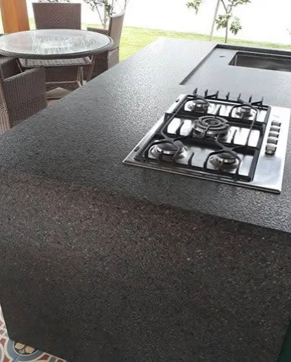 Área gourmet com bancada em pedra escura e cooktop